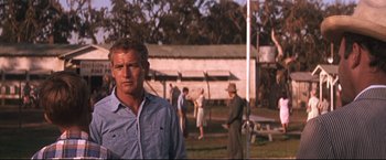 Movie still from “Cool Hand Luke” (1967), directed by Stuart Rosenberg – A man standing in front of a group of people in a field; Medium shot, Over the shoulder angle