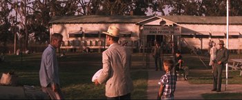 Movie still from “Cool Hand Luke” (1967), directed by Stuart Rosenberg – A man holding a white frisbee in a field; Wide shot, Over the shoulder angle