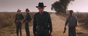 Movie still from “Cool Hand Luke” (1967), directed by Stuart Rosenberg – A man in a hat and sunglasses standing on the side of a road; Medium shot, Low angle