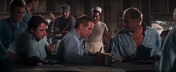 Movie still from “Cool Hand Luke” (1967), directed by Stuart Rosenberg – A group of men standing around a table; Medium shot, Over the shoulder angle