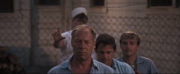 Movie still from “Cool Hand Luke” (1967), directed by Stuart Rosenberg – A group of men standing next to each other in front of a chain link fence; Medium shot, Low angle