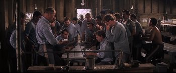 Movie still from “Cool Hand Luke” (1967), directed by Stuart Rosenberg – A group of men standing around a table; Medium shot, High angle