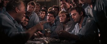 Movie still from “Cool Hand Luke” (1967), directed by Stuart Rosenberg – A group of men sitting around a table with rocks; Medium shot, High angle