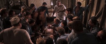 Movie still from “Cool Hand Luke” (1967), directed by Stuart Rosenberg – A group of people standing around a man with no shirt; Wide shot, High angle