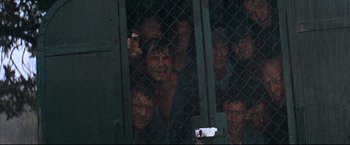 Movie still from “Cool Hand Luke” (1967), directed by Stuart Rosenberg – A group of people behind a chain link fence; Wide shot, High angle