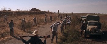 Movie still from “Cool Hand Luke” (1967), directed by Stuart Rosenberg – A group of men in a field with a rifle; Wide shot, High angle