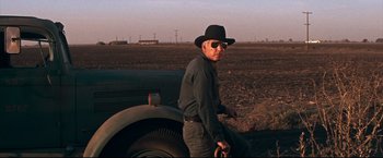 Movie still from “Cool Hand Luke” (1967), directed by Stuart Rosenberg – A man standing next to an old car in a field; Medium shot, Low angle