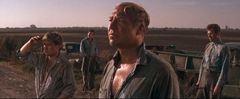 Movie still from “Cool Hand Luke” (1967), directed by Stuart Rosenberg – A man standing in a field with other men; Medium shot, Low angle