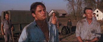 Movie still from “Cool Hand Luke” (1967), directed by Stuart Rosenberg – A man in a blue shirt is standing next to a truck; Medium shot, Low angle