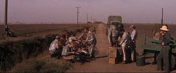 Movie still from “Cool Hand Luke” (1967), directed by Stuart Rosenberg – A group of men sitting on the side of a road; Wide shot, High angle