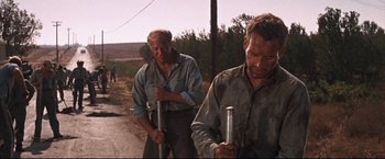 Movie still from “Cool Hand Luke” (1967), directed by Stuart Rosenberg – A couple of men standing next to each other on a dirt road; Medium shot, Low angle