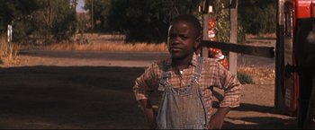 Movie still from “Cool Hand Luke” (1967), directed by Stuart Rosenberg – A young boy wearing overalls standing on the side of the road; Medium shot, Low angle