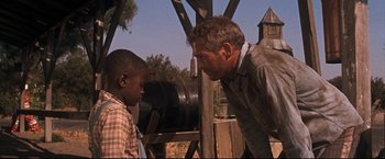 Movie still from “Cool Hand Luke” (1967), directed by Stuart Rosenberg – A man and a young boy talking to each other outside; Medium shot, Over the shoulder angle