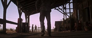 Movie still from “Cool Hand Luke” (1967), directed by Stuart Rosenberg – A man standing in a barn with other men standing in the background; Wide shot, Low angle