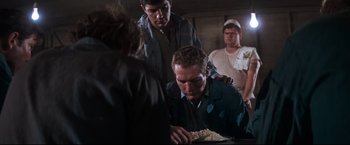 Movie still from “Cool Hand Luke” (1967), directed by Stuart Rosenberg – A group of people standing around a man eating food; Medium shot, Low angle