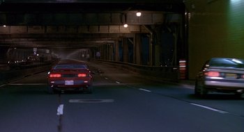 Movie still from “Cop Land” (1997), directed by James Mangold – A red car driving down a street at night; Wide shot, High angle