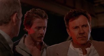 Movie still from “Cop Land” (1997), directed by James Mangold – Two men standing next to each other in front of a building; Close Up shot, Low angle