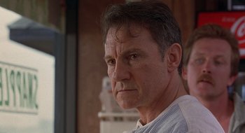 Movie still from “Cop Land” (1997), directed by James Mangold – A person wearing a shirt looking at the camera; Close Up shot, Low angle