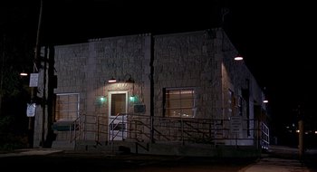 Movie still from “Cop Land” (1997), directed by James Mangold – A building that has a railing in front of it at night; Extreme Wide shot, Low angle