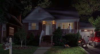 Movie still from “Cop Land” (1997), directed by James Mangold – A man standing on a porch looking out a window at night; Extreme Wide shot, Low angle