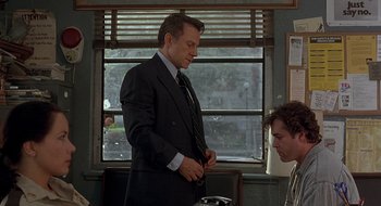 Movie still from “Cop Land” (1997), directed by James Mangold – A man in a suit and tie standing next to a man; Medium shot, Over the shoulder angle