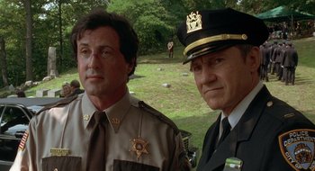 Movie still from “Cop Land” (1997), directed by James Mangold – Two police officers standing next to each other in a park; Close Up shot, Low angle