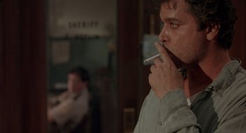 Movie still from “Cop Land” (1997), directed by James Mangold – A man is smoking a cigarette in front of a mirror; Close Up shot, Over the shoulder angle