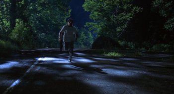 Movie still from “Cop Land” (1997), directed by James Mangold – A man is running on a dark road at night; Extreme Wide shot, High angle