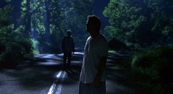 Movie still from “Cop Land” (1997), directed by James Mangold – Two people walking down a street at night; Wide shot, Over the shoulder angle