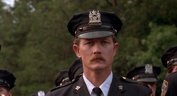 Movie still from “Cop Land” (1997), directed by James Mangold – A man in a police officer's uniform with a mustache; Close Up shot, Low angle