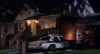 Movie still from “Cop Land” (1997), directed by James Mangold – A police car parked in front of a house at night; Wide shot, High angle
