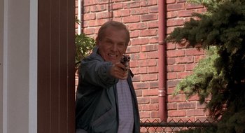 Movie still from “Cop Land” (1997), directed by James Mangold – An older man holding a gun in front of a brick wall; Medium shot, Low angle