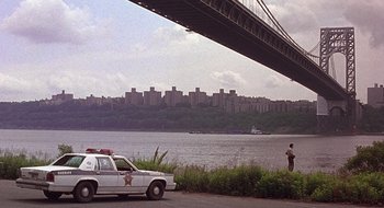 Movie still from “Cop Land” (1997), directed by James Mangold – A police car parked on the side of a river; Extreme Wide shot, Low angle