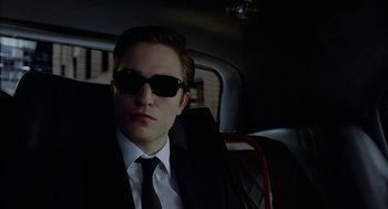 Movie still from “Cosmopolis” (2012), directed by David Cronenberg – A man in a suit and sunglasses sitting in the back of a car; Close Up shot, Low angle