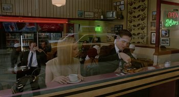 Movie still from “Cosmopolis” (2012), directed by David Cronenberg – A man and a woman sitting at a counter; Medium shot, High angle