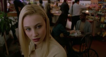 Movie still from “Cosmopolis” (2012), directed by David Cronenberg – A woman with blonde hair and blue eyes in front of a group of diners in a restaurant; Close Up shot, Over the shoulder angle