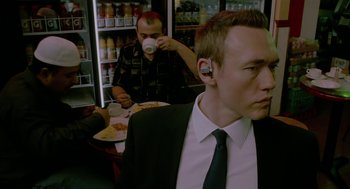 Movie still from “Cosmopolis” (2012), directed by David Cronenberg – A man in a suit and tie drinking a cup of coffee; Close Up shot, Over the shoulder angle
