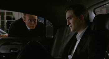 Movie still from “Cosmopolis” (2012), directed by David Cronenberg – A man sitting in a car looking at another man in a suit; Medium shot, Over the shoulder angle