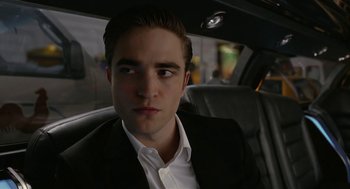 Movie still from “Cosmopolis” (2012), directed by David Cronenberg – A person sitting in a car wearing a suit; Close Up shot, Low angle