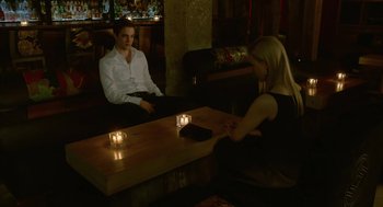 Movie still from “Cosmopolis” (2012), directed by David Cronenberg – A man and a woman sitting at a table with lit candles; Medium shot, High angle