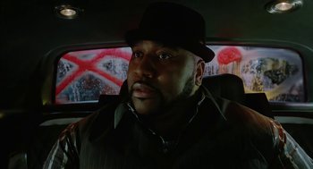 Movie still from “Cosmopolis” (2012), directed by David Cronenberg – A man in a hat sitting in the back seat of a car; Close Up shot, Low angle