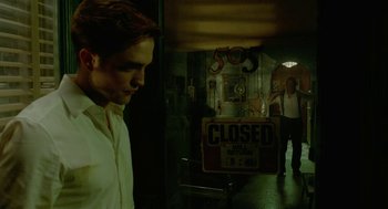 Movie still from “Cosmopolis” (2012), directed by David Cronenberg – A man standing next to another man in a room; Wide shot, Over the shoulder angle