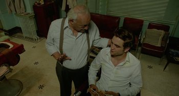 Movie still from “Cosmopolis” (2012), directed by David Cronenberg – A man looking at a cell phone with an older man; Medium shot, Over the shoulder angle