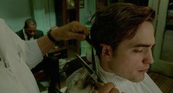 Movie still from “Cosmopolis” (2012), directed by David Cronenberg – A man getting his hair cut by a barber; Close Up shot, Over the shoulder angle
