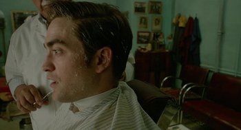 Movie still from “Cosmopolis” (2012), directed by David Cronenberg – A man sitting in front of a mirror in a barber shop; Close Up shot, Over the shoulder angle