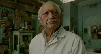 Movie still from “Cosmopolis” (2012), directed by David Cronenberg – An old man with a mustache wearing a white shirt; Close Up shot, Low angle