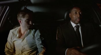 Movie still from “Cosmopolis” (2012), directed by David Cronenberg – Two men sitting in the back seat of a car; Medium shot, Over the shoulder angle
