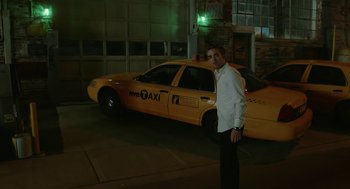 Movie still from “Cosmopolis” (2012), directed by David Cronenberg – A man standing in front of a yellow taxi cab at night; Wide shot, Low angle