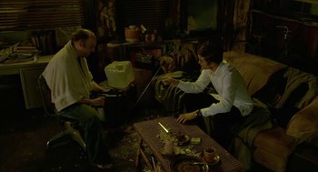 Movie still from “Cosmopolis” (2012), directed by David Cronenberg – Two men sitting on a couch in a living room; Wide shot, High angle