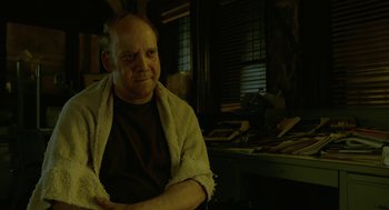 Movie still from “Cosmopolis” (2012), directed by David Cronenberg – An older man sitting in a chair in a room; Medium shot, Low angle